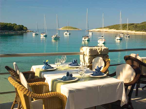 Served tables in beach restaurant near lagoon with yachts