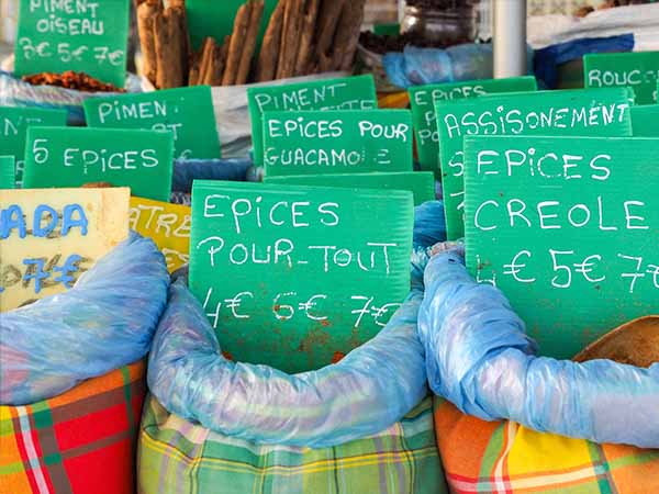 Several bags containing typical spices for cooking with tags reporting names and prices are exposed on a market stall along the road in Sainte Anne Guadeloupe.